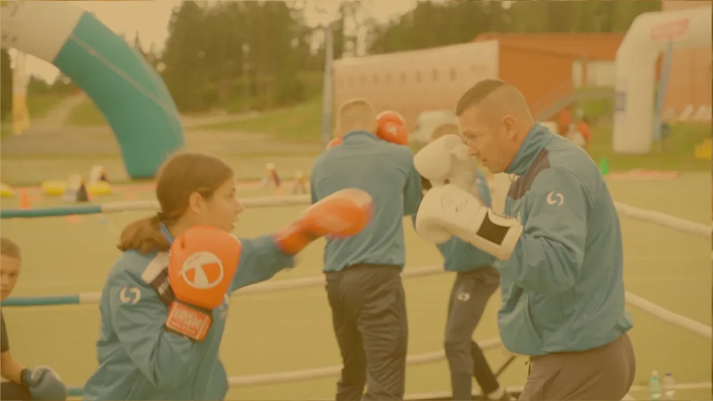 Dievča v boxerských rukaviciach trénuje údery s trénerom na vonkajšom športovom podujatí