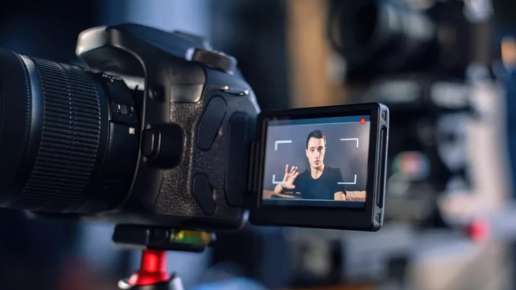 Displej DSLR kamery zobrazuje muža hovoriaceho počas nahrávania osobnej výpovede