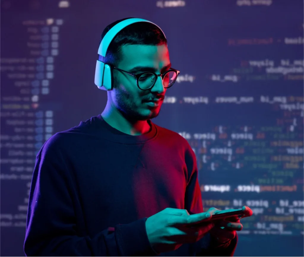 Mladý muž so slúchadlami hrá na smartfóne pred premietaným programovým kódom