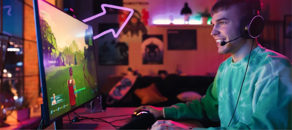 Usmiaty hráč s headsetom hrá farebnú akčnú hru na počítači